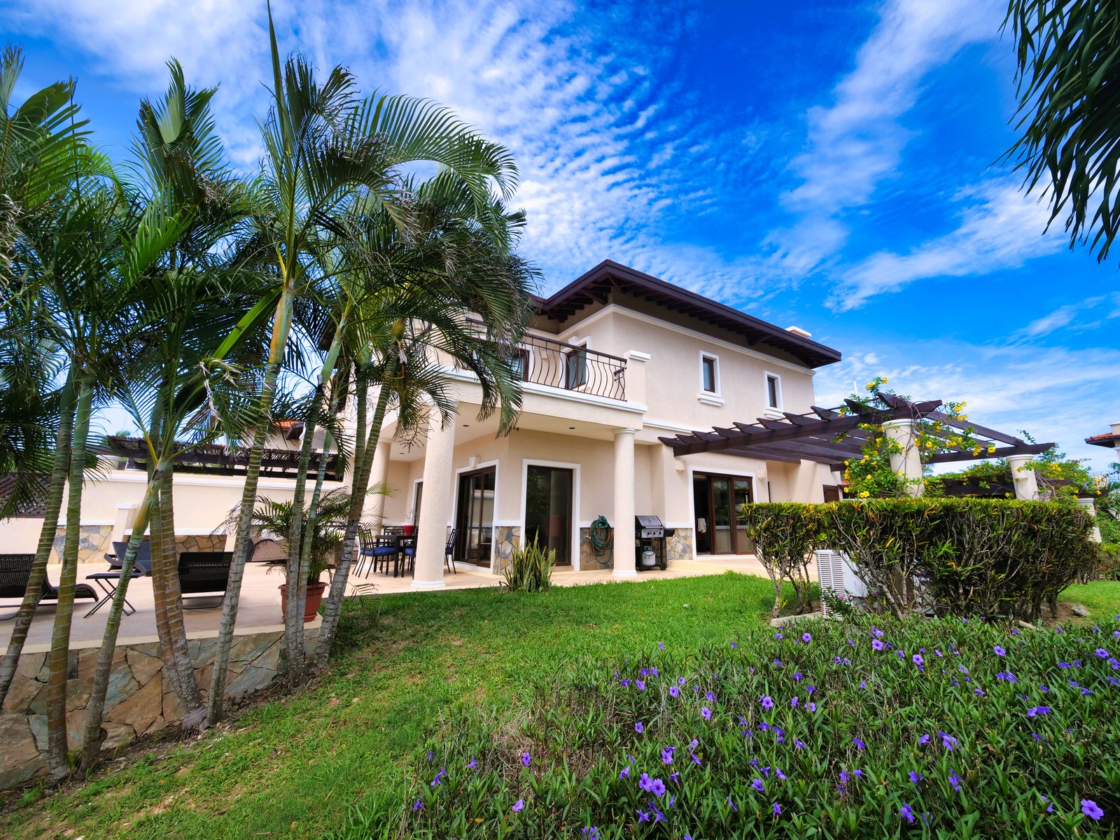 Garden-side view of 1111 Pearl Court with palms, patios, and tropical landscaping